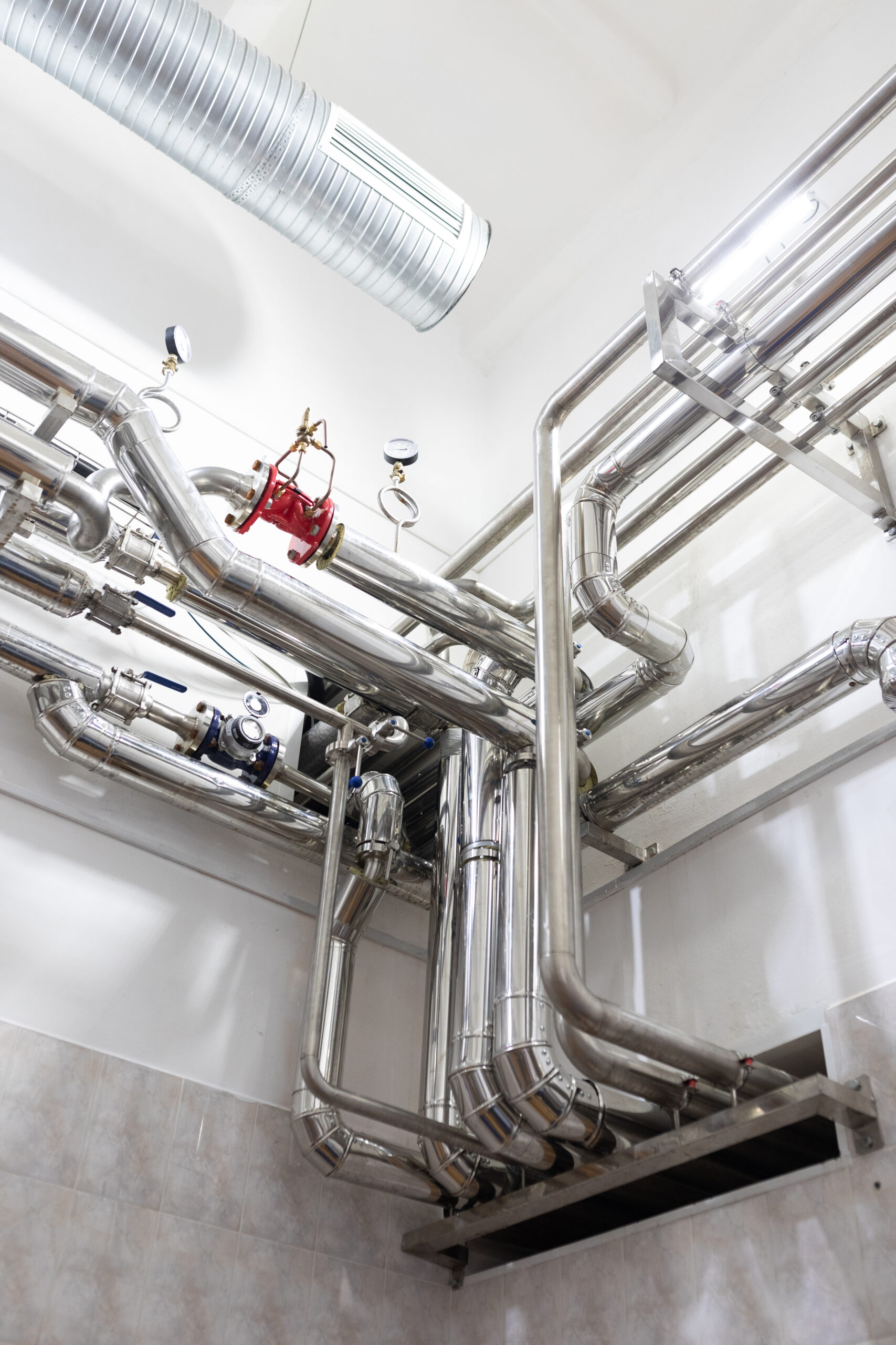 Steel pipelines and cables in factory interior as industrial zone background concept